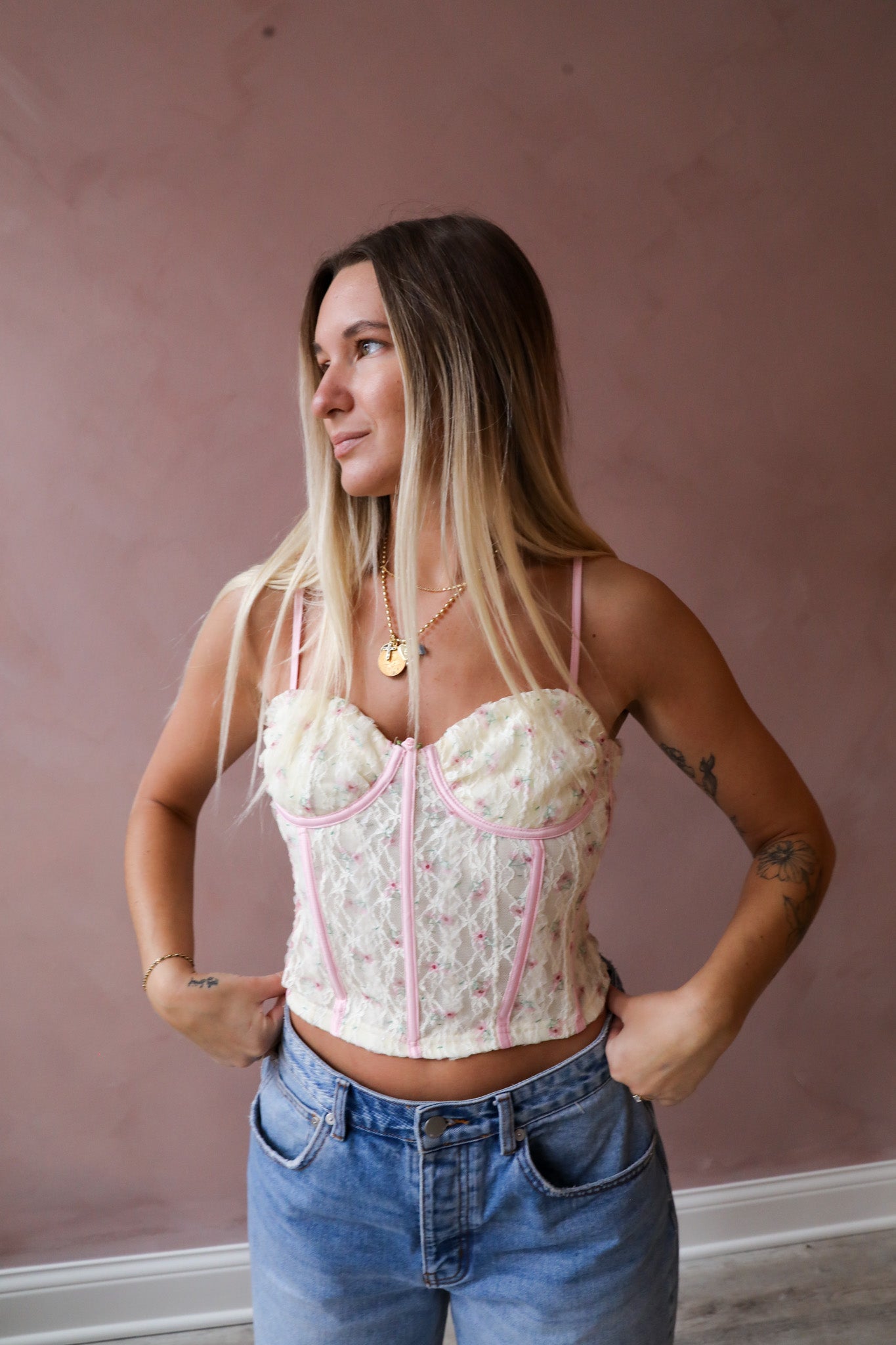 A lace fabric with contrast piping detail adorns this garment, featuring adjustable spaghetti straps and a convenient zipper closure. The piece is fully lined, adding to its practicality and elegance.
